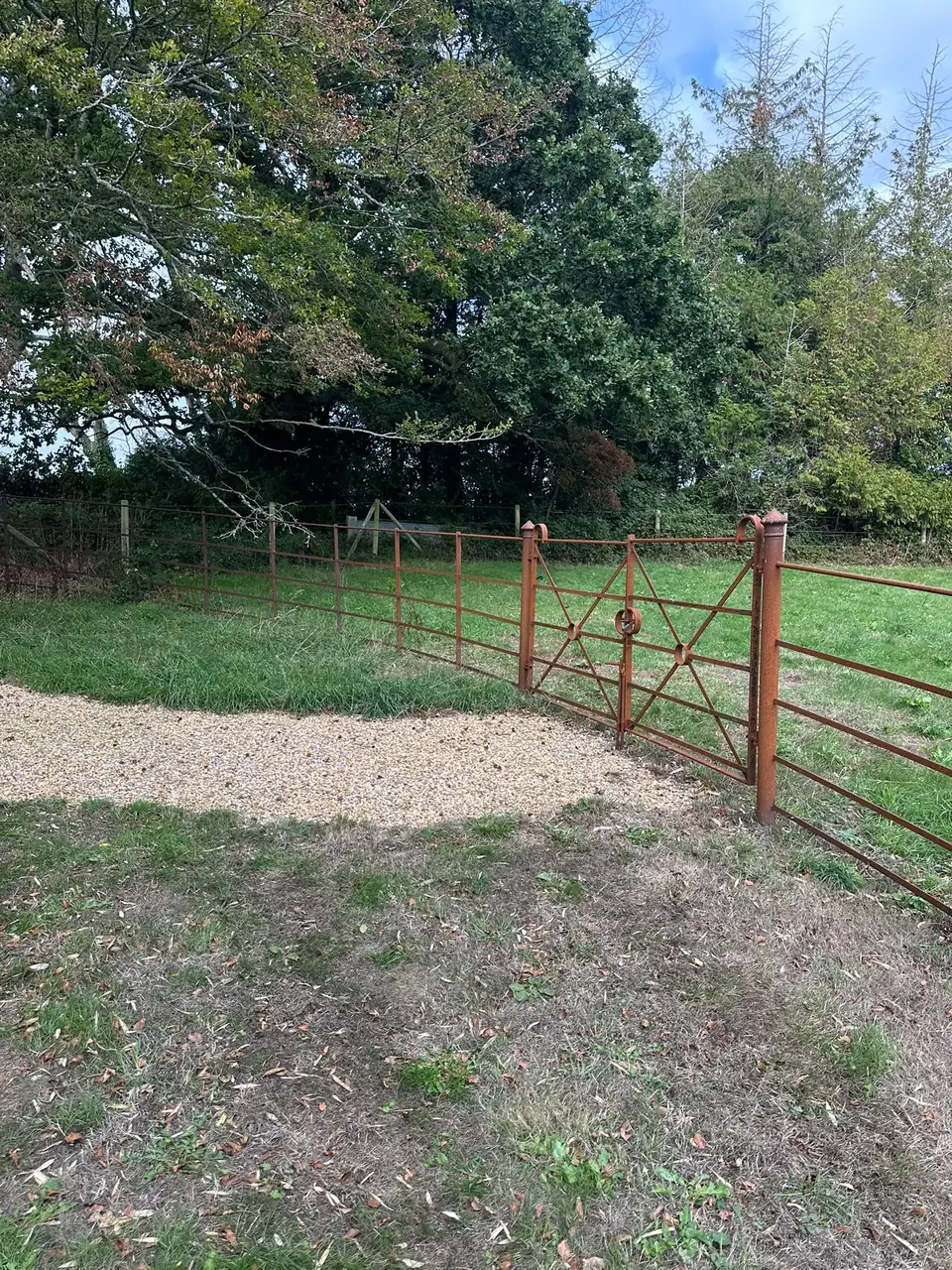 X-braced estate gates and capped gate posts where the gravel track meets the paddock fencing